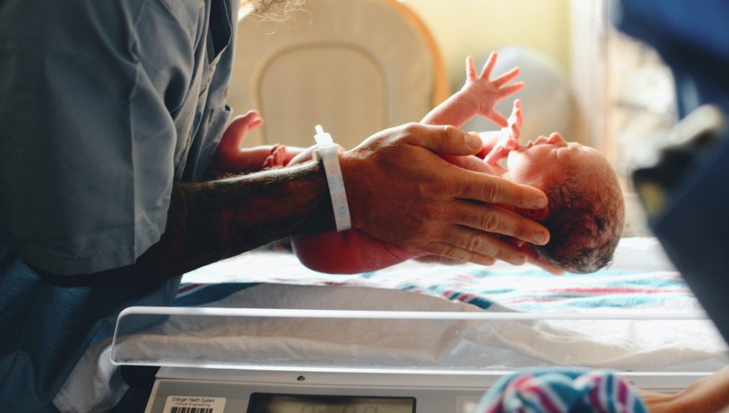 person wearing gray shirt putting baby on scale