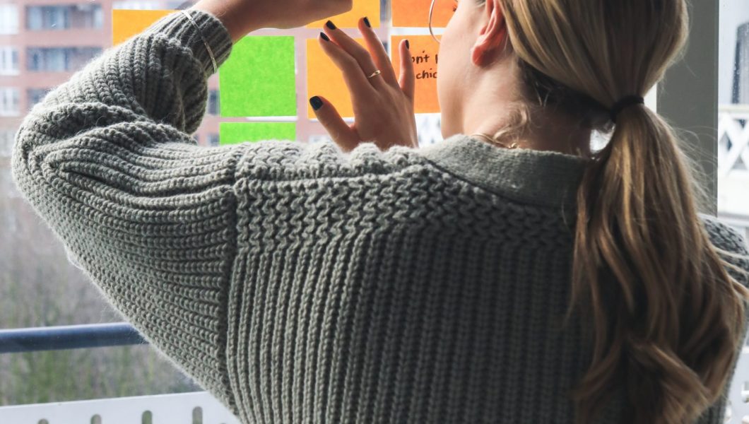 woman in gray sweater holding smartphone